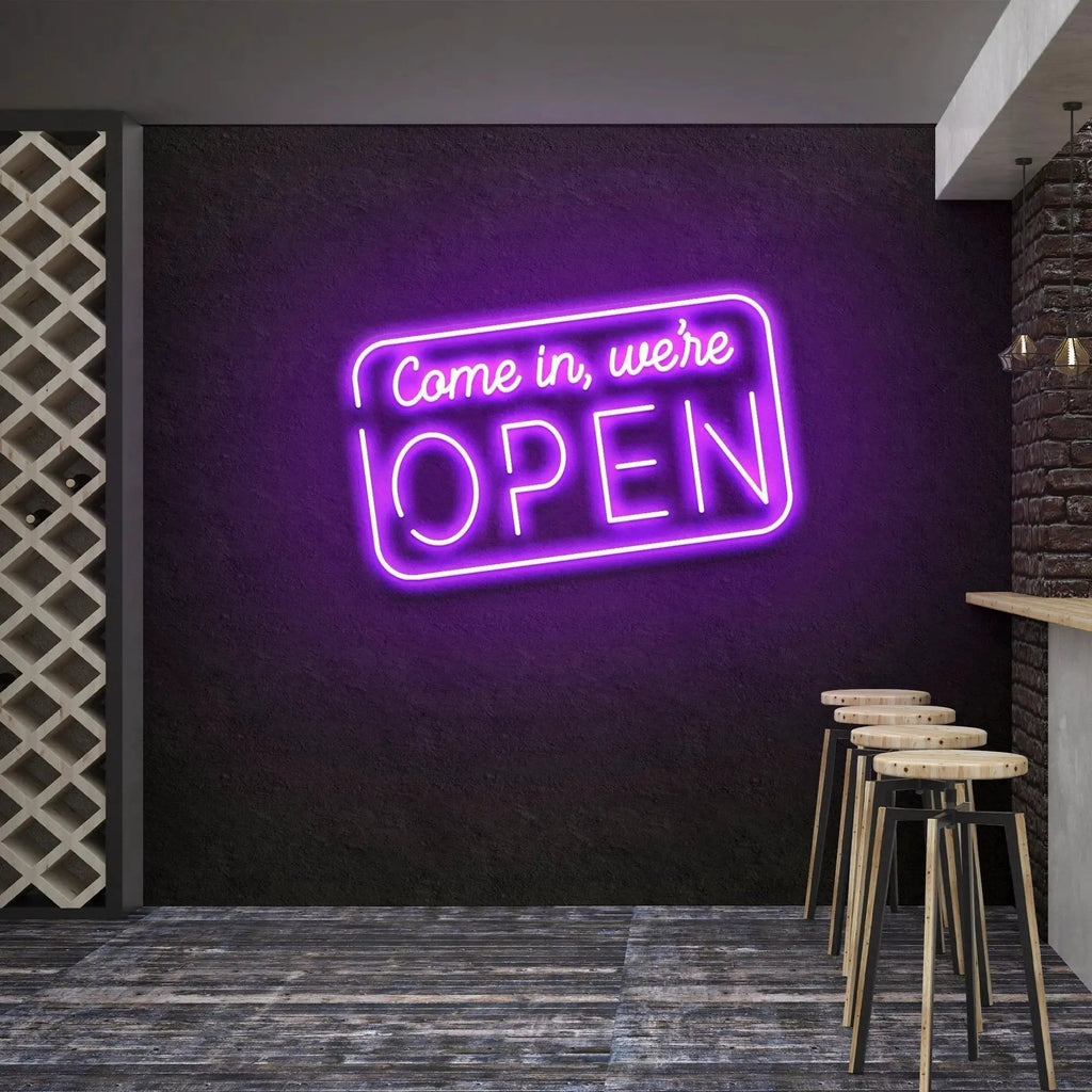 Come In We're Open neon sign glowing violet above bar stools