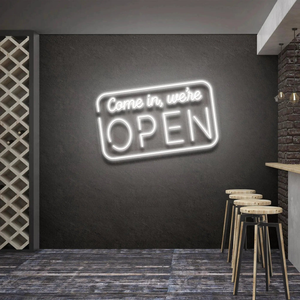 Come In We're Open neon sign glowing cool white above bar stools